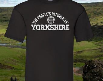 May include: Black t-shirt featuring the text "THE PEOPLE'S REPUBLIC OF YORKSHIRE" in white, arched above the word "YORKSHIRE". A white rose graphic is centered above the word. The shirt is short-sleeved and made of a soft material.
