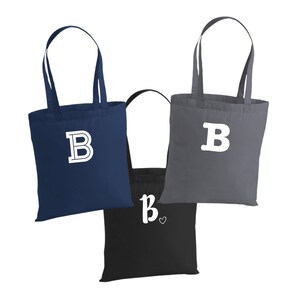 May include: Three tote bags with the letter "B" printed on them. The bags are navy blue, gray, and black. The "B" on the black bag has a heart next to it.
