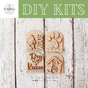 May include: DIY kits featuring four wooden dog-themed designs. Each design is a different shape and includes a paw print, a fire hydrant, a dog house, and the words "Woof" and "Dog Kisses Fix Everything". The kits are perfect for home decor.