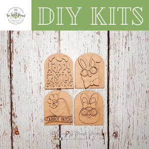 May include: Four unfinished wooden DIY kits for Easter. The kits include a Happy Easter sign, a bunny with glasses and a bow tie, a carrot with a flower, and a bunny with a bow and glasses. The words "DIY KITS" are at the top.