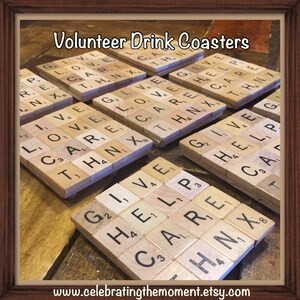 May include: Set of six square drink coasters made from wooden letter tiles. Each coaster features a different word related to volunteerism, such as "give", "love", "care", "help", and "thank".