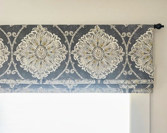 May include: A gray and white patterned roman shade with a black finial on the right side.