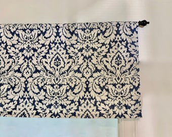 May include: A white valance with a navy blue damask pattern. The valance is hung on a window with a black finial.