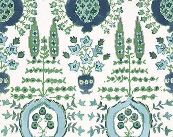 May include: A white fabric with a repeating pattern of green, blue, and white stylized floral designs. The pattern features a central motif of a stylized flower with a blue outline and green and white details.
