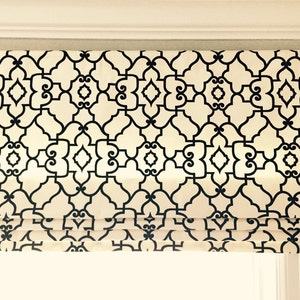 May include: A white roman shade with a black geometric pattern. The shade is pulled up to reveal a window.