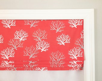 May include: Coral-colored roman shade with a white coral reef pattern. The shade is made of fabric and has a white trim.