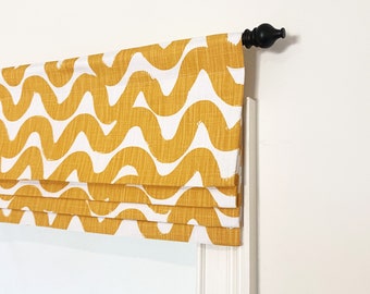 May include: A yellow and white patterned roman shade with a black finial. The shade is made of a textured fabric with a wavy design.