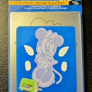 May include: A blue and silver packaging for a Disney Minnie Mouse embossing folder and cutting die set. The packaging features a silhouette of Minnie Mouse with her signature polka dot dress and bow. The text on the packaging reads "Disney Minnie cut & emboss! découpe & gaufrage! 1 embossing folder & 1 cutting die 1 classeur de gaufrage & 1 matrice de découpe".