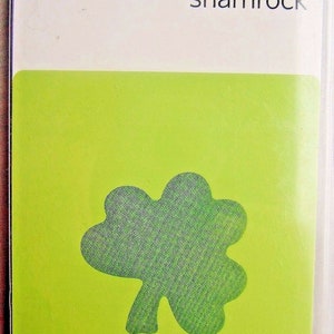 May include: A green shamrock die cut for crafting. The packaging is white with the Quick Kutz logo and the word "shamrock". It says "Includes: one die" at the bottom.