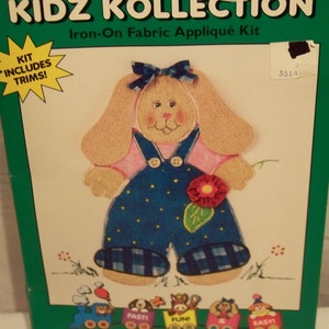 May include: A craft kit for making a dimensional fabric applique of a lop-eared bunny wearing overalls. The kit includes die-cut shapes with Fus-O-Bond already applied and trims to complete one project. The kit is called "Kidz Kollection" and the bunny is named "Lop-Eared Lucy".