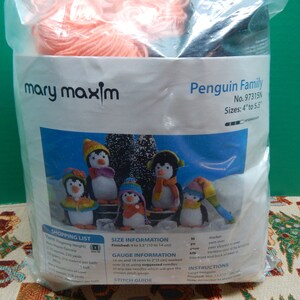 May include: A clear plastic bag containing yarn and a knitting pattern for a Penguin Family. The pattern features images of knitted penguins with colorful hats and scarves. The finished size is 4 to 5.5 inches.