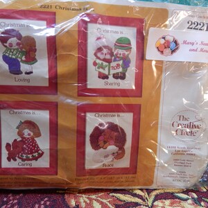 May include: A plastic package containing four cross-stitch patterns featuring children and the text "Christmas is..." with themes of loving, sharing, caring, and peace. The package is labeled "2221" and "Mary's Neat Kits and More".