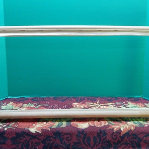 May include: A wooden embroidery hoop with a white fabric stretched across it. The hoop is sitting on a patterned fabric.