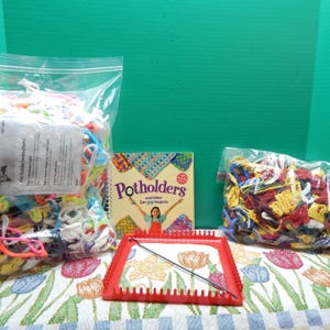 May include: A red plastic loom with a metal hook, two bags of colorful yarn, and a book titled "Potholders and Other Loomed Projects" by Klutz.