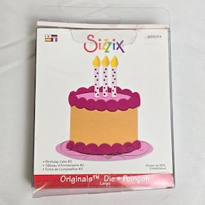 May include: A Sizzix die-cut set featuring a birthday cake design. The cake is yellow with a pink top and base, and three candles with yellow flames. The packaging includes the text "Birthday Cake #2" and "Originals Die".