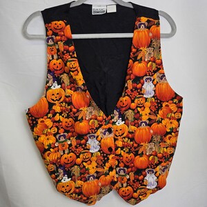 May include: A black vest featuring a vibrant Halloween design. The pattern showcases orange pumpkins, ghosts, teddy bears, and autumn leaves. The vest has a V-neck and is made from a lightweight material.
