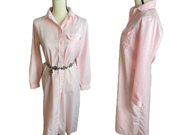 May include: A long-sleeved pink button-down shirt dress with a single chest pocket and a button-up front.