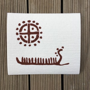 Peut inclure: Un torchon blanc avec un motif brun en forme de cercle avec une croix à l'intérieur et un bateau stylisé avec une queue incurvée.