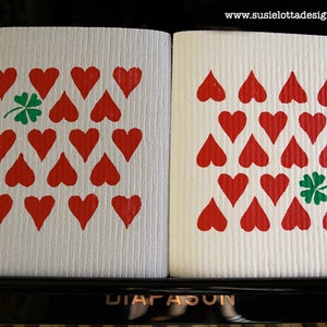 Peut inclure: Deux torchons blancs avec un motif de cœurs rouges et un trèfle vert dans le coin. Les torchons sont étiquetés "DIAFASUN".