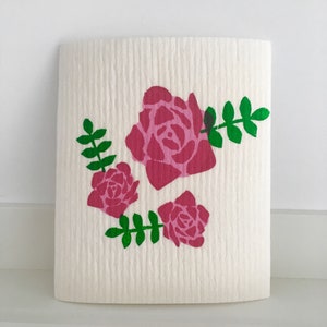 Peut inclure: Éponge de cuisine blanche avec un motif floral rose et vert. Le motif représente trois roses et des feuilles vertes.