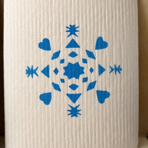 Peut inclure: Une carte blanche avec un motif de flocon de neige bleu. Le flocon de neige est composé de cœurs, d'étoiles et de diamants.