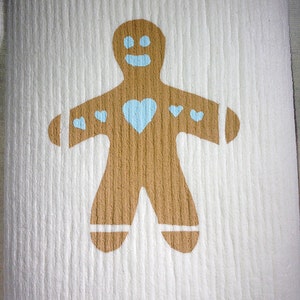 Peut inclure: Un tissu blanc texturé avec un motif de bonhomme en pain d'épices marron. Le bonhomme en pain d'épices a des yeux bleus, un sourire bleu et un cœur bleu. De petits cœurs bleus décorent les bras. Le site web "www.susielottadesigns.com.au" est en bas.