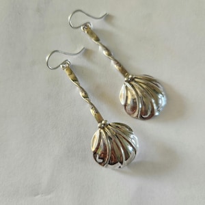 May include: A pair of silver earrings with a twisted wire design and a shell-shaped pendant.
