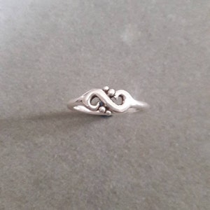 May include: A silver ring with an infinity symbol design. The ring is simple and elegant.