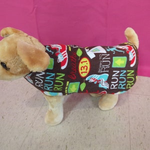 May include: A brown dog sweater with a colorful print featuring the words "Run" and "Born to Run". The print also includes a green leaf, a red shoe, and the number "13.1".