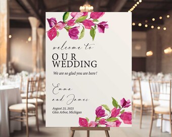 May include: A white wedding welcome sign with pink floral accents. The sign reads "Welcome to Our Wedding" with the names Emma and James, the date August 25, 2025, and the location Glen Arbor, Michigan.
