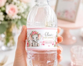 May include: A clear plastic water bottle with a white cap and a custom label featuring a gray elephant with a pink floral crown, pink roses, and the text Olivia's BABY SHOWER 05 | 12 | 28 printed on a white background with pink borders.
