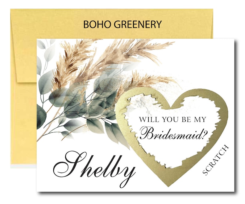 May include: A white card with a gold heart that says "Will you be my Bridesmaid?" with a scratch-off area. The card has a watercolor design of greenery and pampas grass. The name "Shelby" is written in cursive at the bottom of the card.