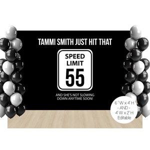 May include: A black backdrop with the text "TAMMI SMITH JUST HIT THAT" and a speed limit sign reading "55." The sign is in a white border. Black, white, and gray balloons frame the backdrop. The text "AND SHE'S NOT SLOWING DOWN ANYTIME SOON!" is below the sign.