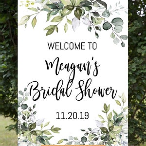 May include: White welcome sign with green watercolor floral border. The text reads "Welcome to Meagan's Bridal Shower 11.20.19".