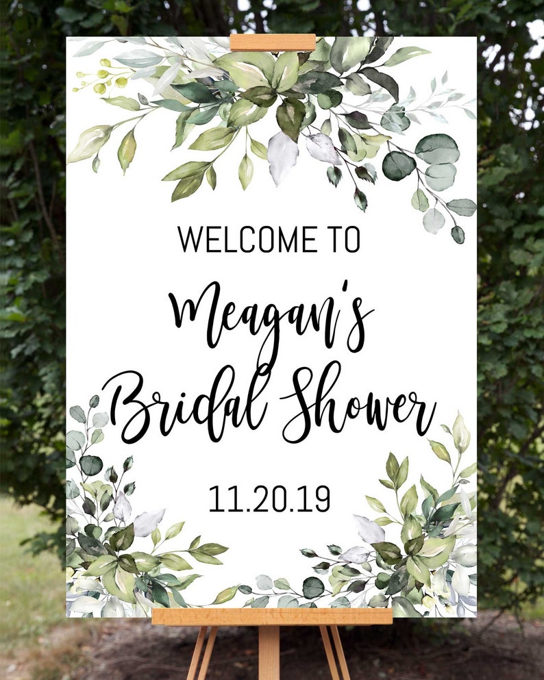 May include: White welcome sign with green watercolor floral border. The text reads "Welcome to Meagan's Bridal Shower 11.20.19".