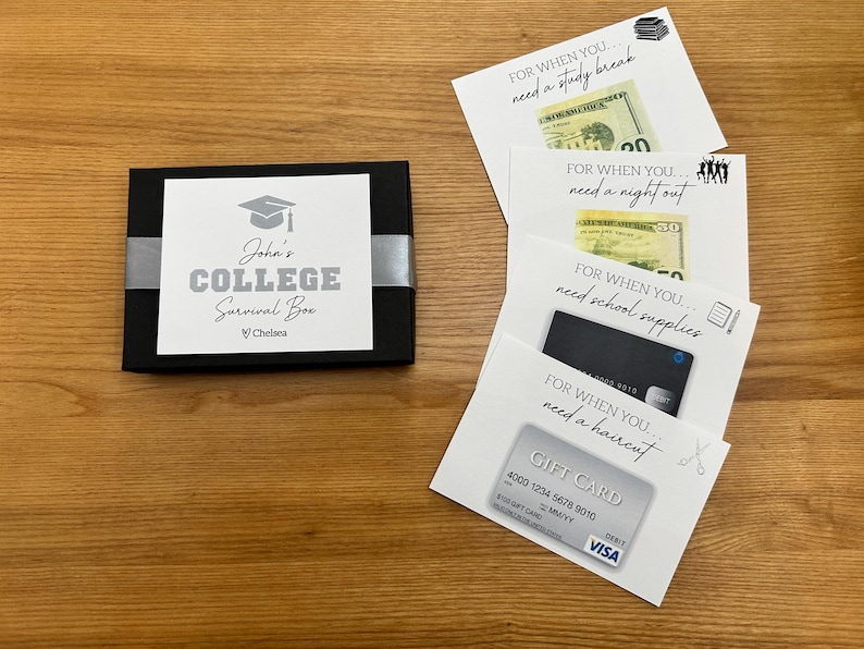 May include: A black box with a white label that reads "John's COLLEGE Survival Box" with a graduation cap graphic. Several white cards with text and money or gift cards are next to the box. The cards say "For when you need a study break", "For when you need a night out", "For when you need school supplies", and "For when you need a haircut".