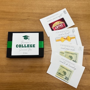 May include: A black box with a green ribbon, labeled "Breanna's College Survival Box." Includes gift cards for a movie night and a treat, cash, and a gift card for laundry. The box is on a wooden surface.