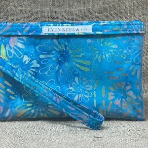 May include: A blue and white floral print clutch bag with a zipper closure and a detachable strap. The bag has a label that reads "Even Keel & Co."