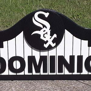 Op de afbeelding: Zwart en wit houten bord met de naam "DOMINIC". Het bord heeft het logo van de Chicago White Sox en een gebogen bovenkant. Het bord is van hout.