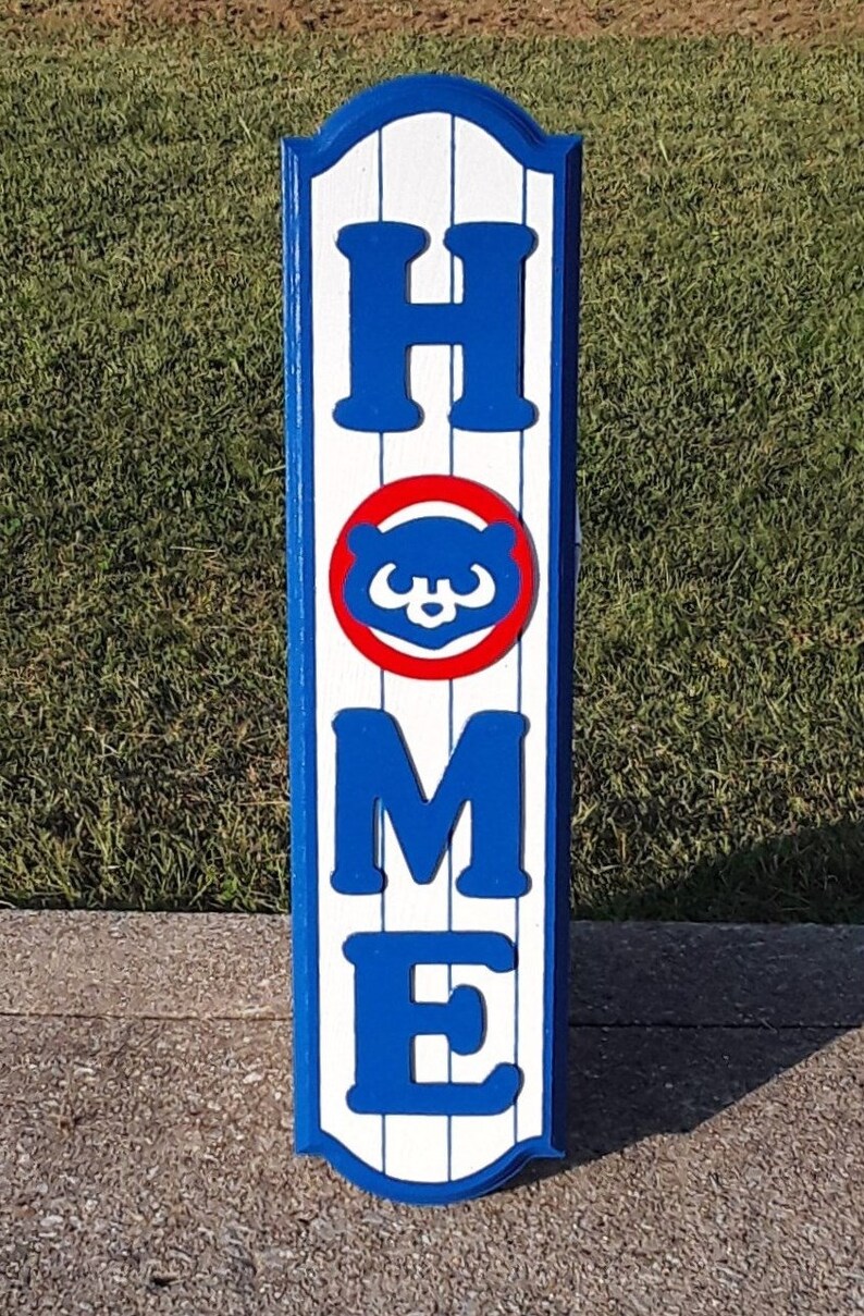 May include: A wooden "HOME" sign with a blue and white striped background. The "O" is replaced with the Chicago Cubs logo, a red circle with a blue bear face.