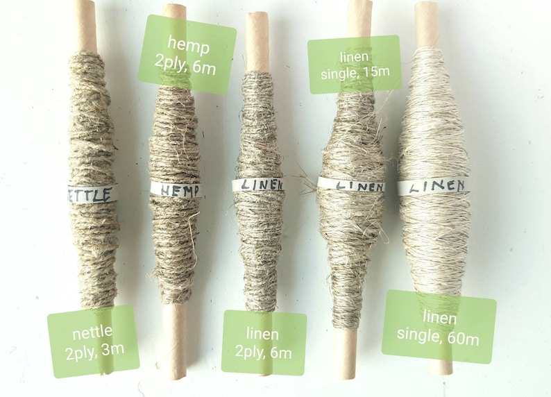 May include: Six spools of natural fiber yarn, including hemp and linen, are displayed on a white surface. The spools are labeled with the type of fiber and the length of the yarn. The labels read: "hemp 2ply, 6m", "linen single, 15m", "nettle 2ply, 3m", "linen 2ply, 6m", and "linen single, 60m".