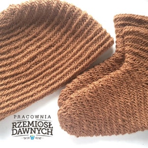 Puede incluir: Un gorro de punto marrón y un par de calcetines de punto marrón. El gorro y los calcetines tienen una textura acanalada. El texto "Pracownia Rzemiosl Dawnych" es visible en la imagen.