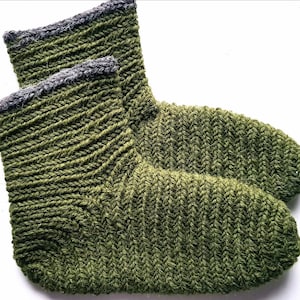 Peut inclure: Une paire de chaussettes en tricot vert avec un bord côtelé gris. Les chaussettes sont faites avec un point de chevrons.