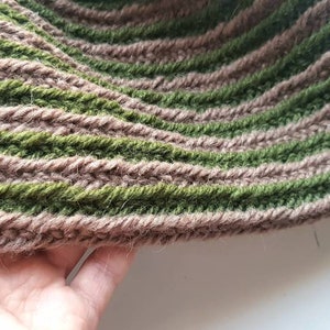 Puede incluir: Primer plano de una bufanda tejida con rayas alternas de hilo marrón y verde.