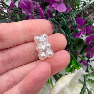May include: A white pearl-like gummy bear charm in the shape of a teddy bear.