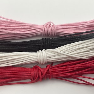 May include: Four spools of waxed cotton cord in different colours: pink, black, white and red.