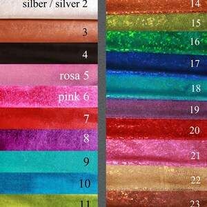 K&ouml;nnte beinhalten: Eine Farbmusterkarte mit 24 verschiedenen Stofffarben. Die Farben sind in Reihen angeordnet und von 1 bis 24 nummeriert. Die Farben umfassen Silber, Gold, Schwarz, Rosa, Rot, Lila, T&uuml;rkis, Blau, Gr&uuml;n und Braun. Der Stoff hat eine schimmernde Oberfl&auml;che.
