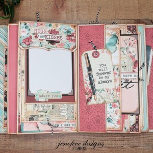 May include: A handmade scrapbook with a floral design, featuring pink, teal, and cream colors. The scrapbook includes decorative elements, tags with text, and a frame for a photo. The text includes "Hugs and Kisses", "adore you", and "I love you".