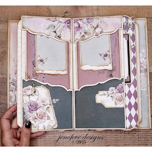 May include: Open scrapbook with a floral design. The pages feature a mix of purple, pink, and gray hues, with decorative elements like roses, butterflies, and tags. The text "jenofeve designs &copy;2025" is visible.