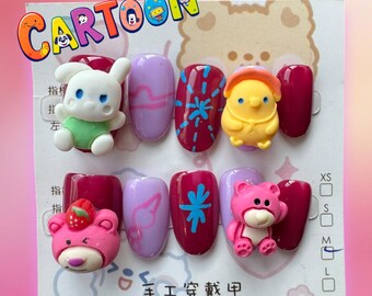 Può includere: Un set di dieci unghie finte con vari disegni di cartoni animati. Le unghie sono dipinte in tonalità di viola e bordeaux. I disegni includono un coniglio, un pulcino, un orso con una fragola, un orso con un fiore e un fiocco di neve blu. Il testo "手工 寄 缺 中" è scritto sulla carta.
